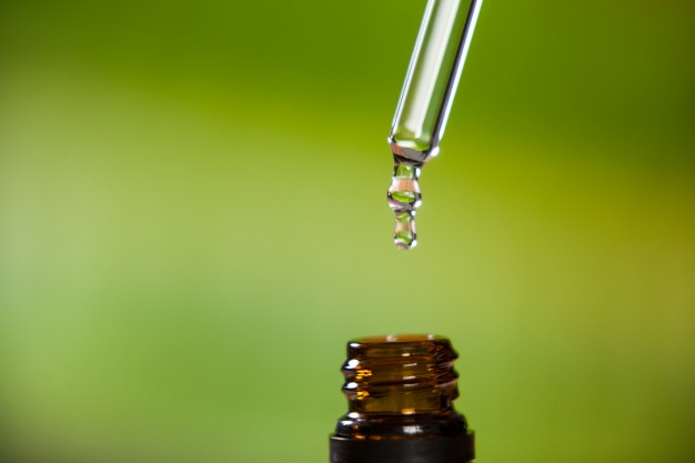 drop-oil-dripping-from-pipette-into-bottle-essential-oil_1252-937